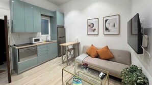 A compact living space with a kitchenette, a sofa, a coffee table, and a TV. - AR Movistar Arena/Wizink centrally located and modern floor (Madrid)