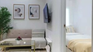 A modern bedroom with a bed, a bedside table, and a chair. There is a TV mounted on the wall and a plant in the corner. - AR Movistar Arena/Wizink centrally located and modern floor (Madrid)