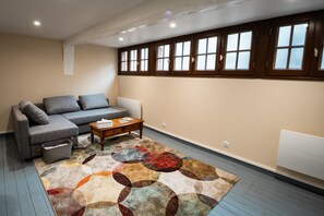 A living room with a sofa, coffee table, and a patterned rug. - Guesthouse “Murmures De La Risle” in Pont-Audemer, Normandy (Pont-Audemer)