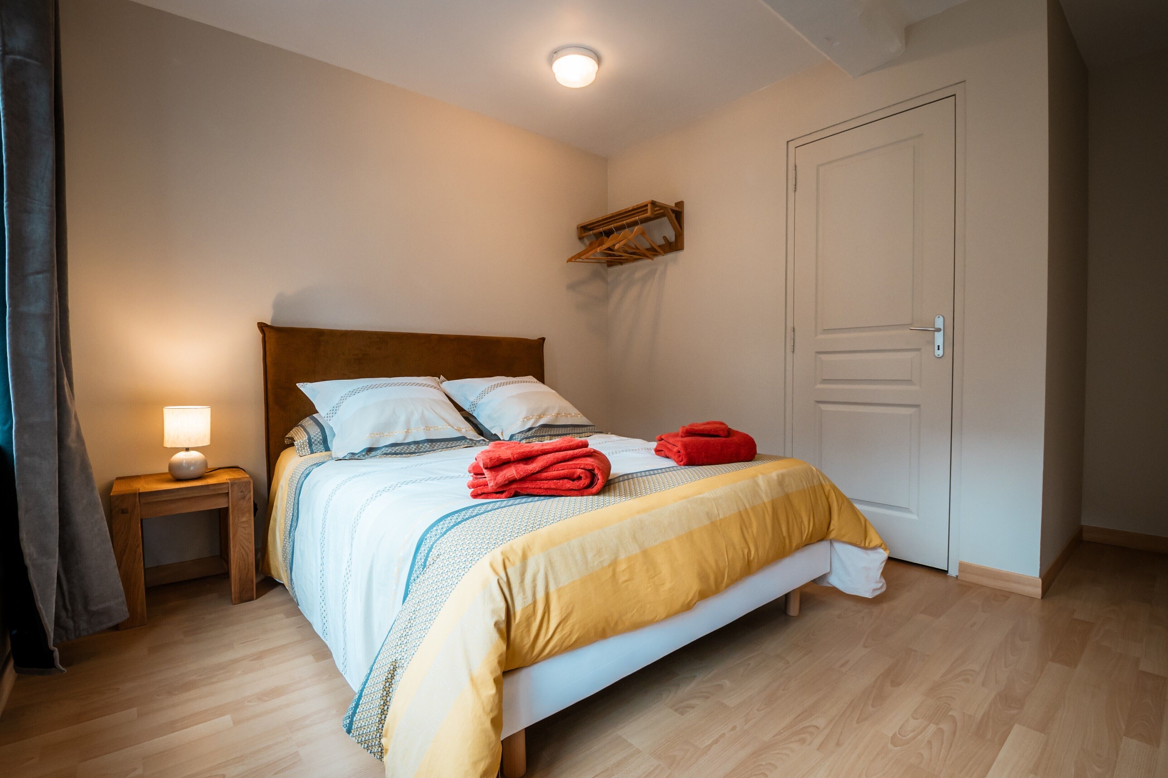 A bedroom with a bed, bedside table, lamp, and a door.