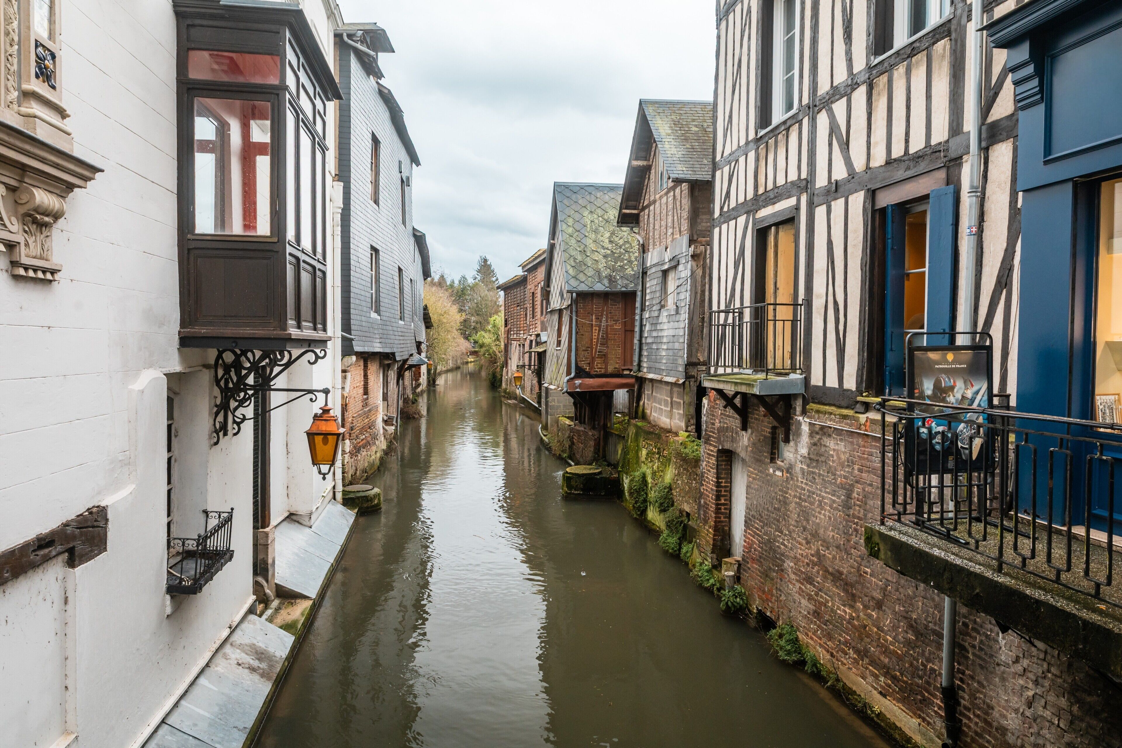 A narrow waterway flanked by historic buildings with balconies and a lantern.
