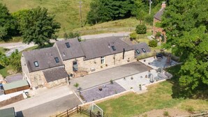 A large stone building with multiple rooms, a paved courtyard, and a fenced area with outdoor seating. - 2 Bed in Ashbourne (oc-dcbob) (Kniveton)