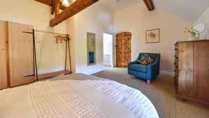 A bedroom with a bed, wooden wardrobe, a blue armchair, and a large mirror. - 2 Bed in Ashbourne (oc-dcbob) (Kniveton)