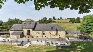 A stone farmhouse with a sloped roof, a small porch, and a garden area with outdoor seating. - 2 Bed in Ashbourne (oc-dcbob) (Kniveton)