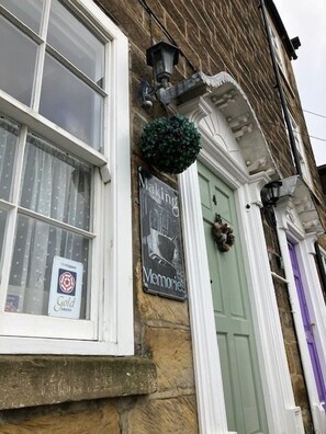 A building with a green door, a sign reading "Making Memories," and a gold award sign on the window. - 2 Bed in Whitby (oc-w050) (Whitby)