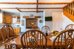A dining area with a wooden table and chairs, a kitchen with wooden cabinets, and a sign above the table. - 2 Bed in Whitby (oc-w050) (Whitby)