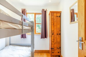 A bunk bed, a wardrobe, and a window with curtains in a room. - 3 Bed in Shebbear (oc-l32583) (Shebbear)