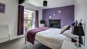 Une chambre à coucher avec un lit, une cheminée, une fenêtre avec des rideaux et un radiateur.