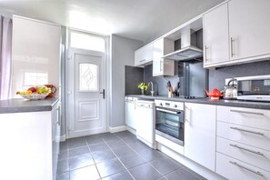 A modern kitchen with white cabinets, a built-in oven, and a microwave.