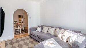 A living room with a grey sofa, a checkered rug, and a dining area with a table and chairs. - 3 Bed in Harrogate (oc-d32616) (Harrogate)
