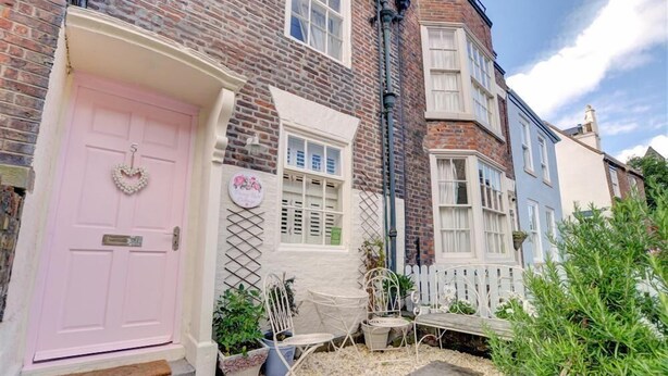 A pink door with a heart-shaped decoration, a white door with shutters, and a white picket fence. - 2 Bed in Whitby (oc-w075) (Whitby)