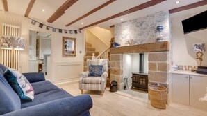 A cozy living room with a fireplace, a striped armchair, and a sofa with decorative pillows. - 2 Bed in Whitby (oc-w075) (Whitby)