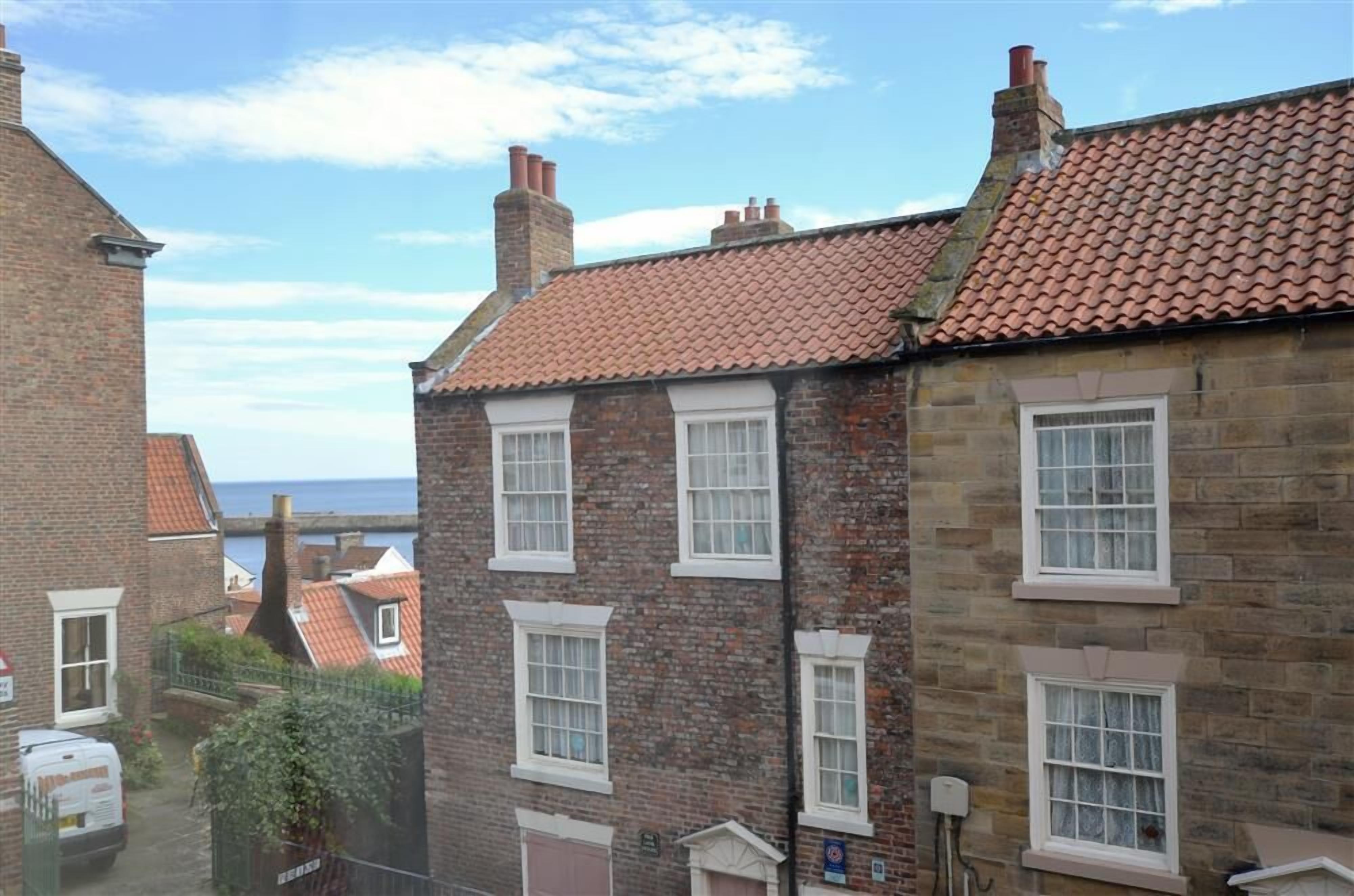 A row of brick houses with red-tiled roofs and white-framed windows.