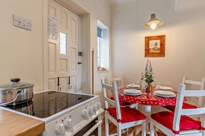 A kitchen with a stove, a dining table with red chairs, and a small plant on the table. - 2 Bed in Whitby (oc-w069) (Whitby)