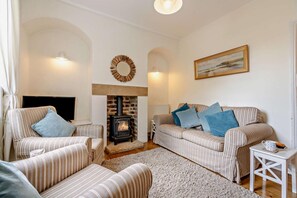 A cozy living room with a fireplace, striped sofas, and a television. - 2 Bed in Whitby (oc-w069) (Whitby)
