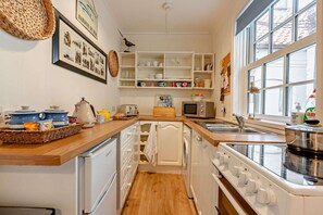 A kitchen with white cabinets, a wooden countertop, a sink, a microwave, and a window. - 2 Bed in Whitby (oc-w069) (Whitby)