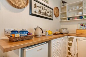 A kitchen with a white refrigerator, a coffee maker, a toaster, and a basket of tea bags. - 2 Bed in Whitby (oc-w069) (Whitby)