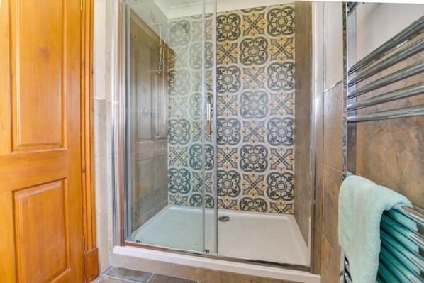 A shower with a glass door, patterned tiles, and a towel rack. - 3 Bed in Llanrhidian (oc-hh476) (Pen-clawdd)