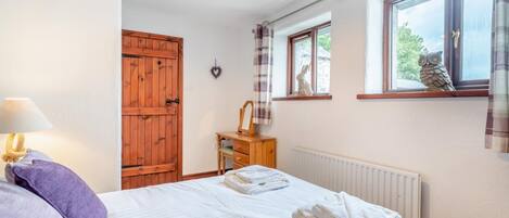 Ein Schlafzimmer mit einem Bett, einem Holzschrank, einer Kommode, einem Fenster mit Vorhängen und einer Heizung.