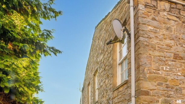 Un étroit sentier de pierres mène à un bâtiment surmonté d’une antenne parabolique et sur lequel on peut lire l’inscription « CHURCH VIEW ».