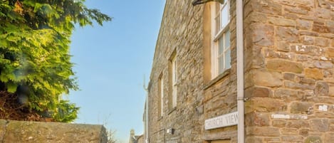 A narrow stone pathway leading to a building with a satellite dish and a sign reading "CHURCH VIEW".