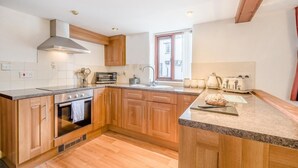 Una cocina moderna con armarios de madera, horno empotrado, microondas y tostadora.