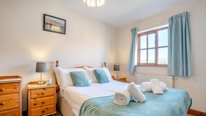 A neatly arranged bedroom with a bed, bedside tables, a lamp, a picture on the wall, and a window with curtains. - 2 Bed in Whitby (oc-w086) (Whitby)