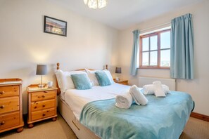 A neatly arranged bedroom with a bed, bedside tables, a lamp, a picture on the wall, and a window with curtains. - 2 Bed in Whitby (oc-w086) (Whitby)