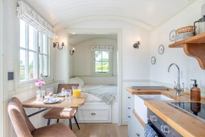 Eine gemütliche Küche mit Essbereich, einem Bett und Blick auf Grünflächen.