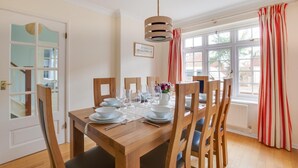Une salle à manger avec une table en bois dressée pour quatre personnes, entourée de chaises.
