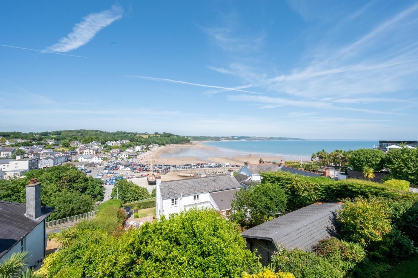 A coastal town with a beach, houses, and greenery.