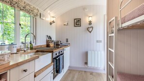 A compact kitchen with a wooden countertop, built-in oven, and a window overlooking greenery. - 2 Bed in Barsham (oc-s32505) (Barsham)