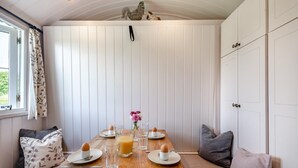 A breakfast setup with a wooden table, plates, cups, and a pitcher of orange juice. - 2 Bed in Barsham (oc-s32505) (Barsham)