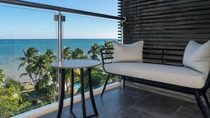 Ein Balkon mit Blick auf den Ozean, einem runden Tisch und einer gepolsterten Sitzecke.
