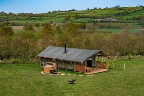 A rustic cabin with a metal roof, wooden deck, and a hot tub. - 3 Bed in Talybont-on-Usk (oc-wal376) (Talybont-on-Usk)