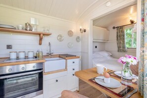 A compact kitchen with a stove, sink, and wooden countertop.