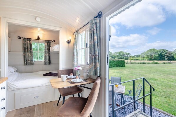 A cozy bedroom with a bed, a desk, and a view of a grassy field.