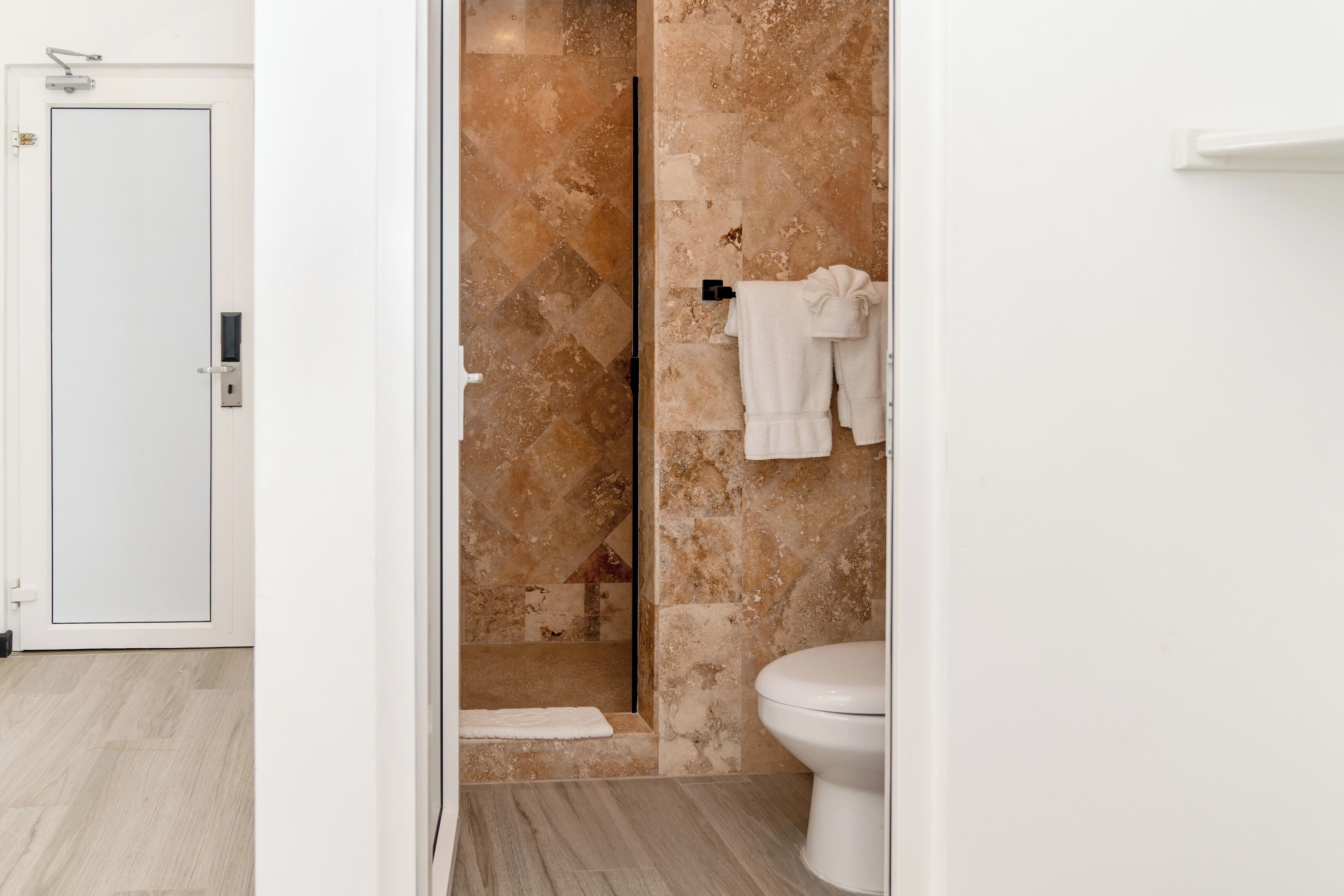Une salle de bain avec une douche, des toilettes et un porte-serviettes.