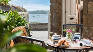 A table set with croissants, a teapot, and a vase of flowers, overlooking a coastal view. - 2 Bed in St. Ives (oc-3wd) (St Ives)
