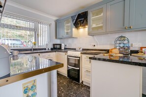 A modern kitchen with white cabinets, a built-in oven, a microwave, and a coffee machine. - 3 Bed in Saundersfoot (oc-pw230) (Saundersfoot)