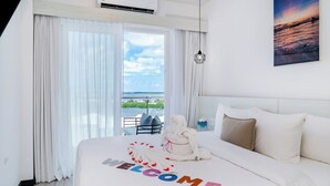 Ein Hotelzimmer mit Bett, Meerblick und einem Bild an der Wand.