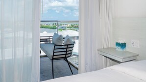 Ein Balkon mit Tisch und Stühlen, einem Bett und einem Fenster mit Vorhängen.