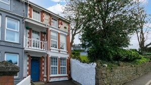 A two-story residential building with a blue door, white railings, and a stone wall. - 1 Bed in Mumbles (oc-hh72) (The Mumbles)