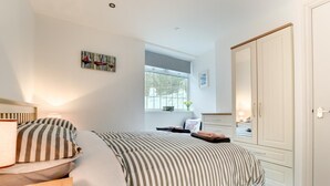 A bedroom with a bed, bedside tables, a window, a wardrobe, and a painting on the wall. - 1 Bed in Mumbles (oc-hh72) (The Mumbles)