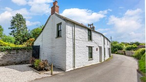 A white two-story house with a chimney, a gravel driveway, and a stone wall. - 2 Bed in Bodmin (oc-p00429) (Saint Teath)