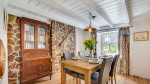 A dining area with a wooden table, chairs, a stone wall, and a wooden cabinet. - 2 Bed in Bodmin (oc-p00429) (Saint Teath)