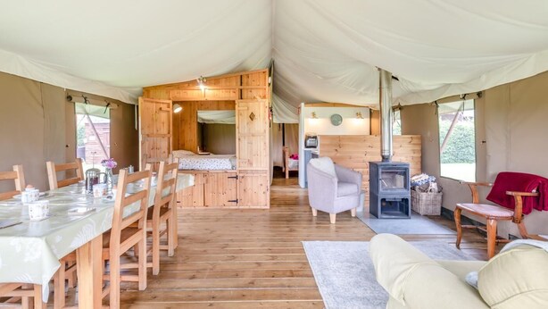 A tented accommodation with a dining area, a sleeping loft, a seating area with a fireplace, and a small kitchenette. - 3 Bed in Barsham (oc-g32508) (Barsham)
