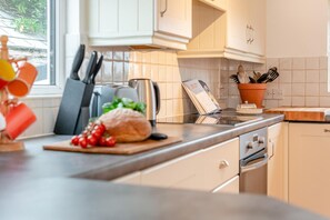 A modern kitchen with white cabinets, a stainless steel stove, and a wooden countertop. - 3 Bed in Padstow (oc-p00043) (Saint Merryn)