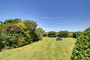 A well-maintained grassy area with a picnic table and dense shrubbery on either side. - 3 Bed in Padstow (oc-p00043) (Saint Merryn)