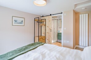 Un dormitorio con cama, armario de madera, zona de ducha y un cuadro en la pared.